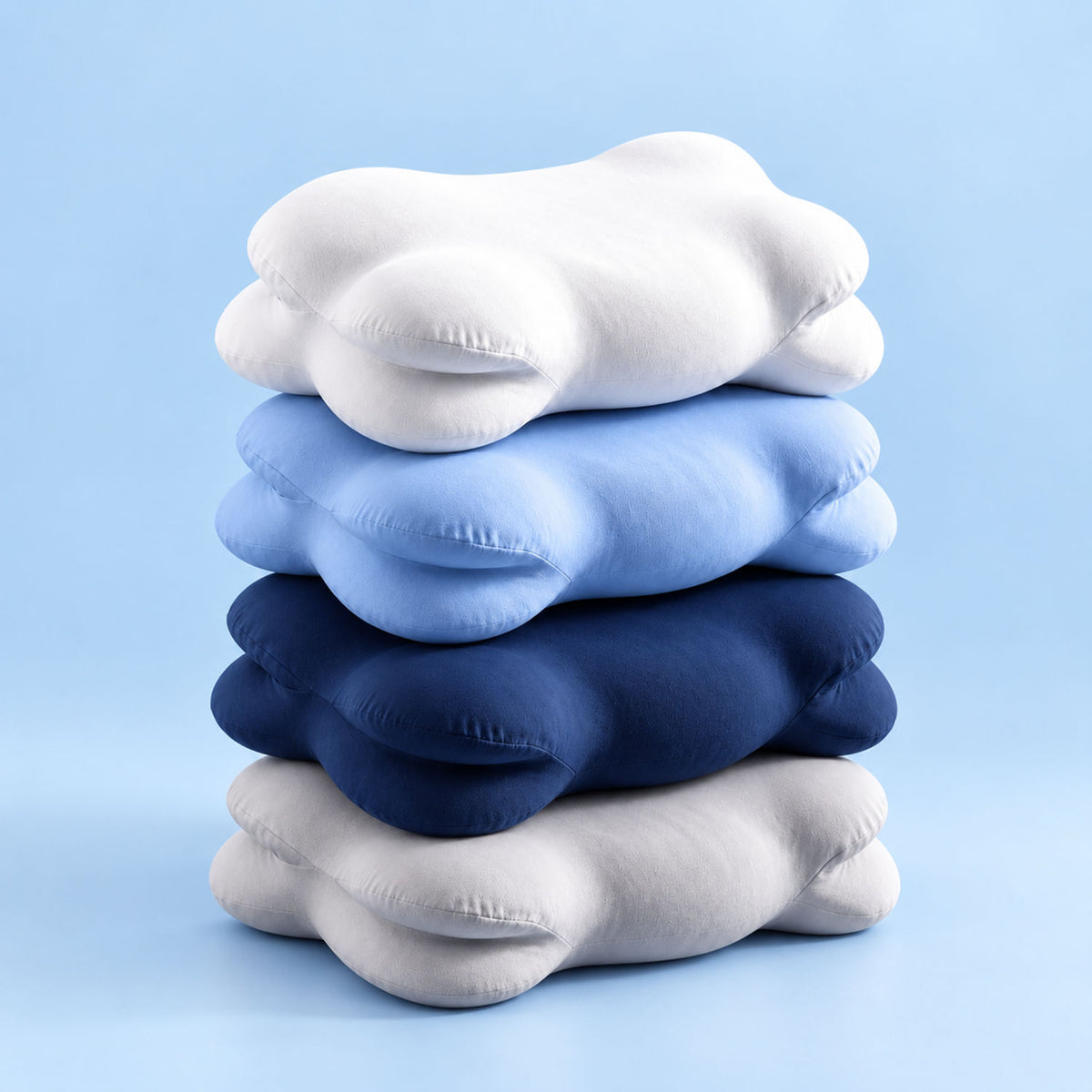 Quatre oreillers NUAGE empilés : blanc, bleu ciel, bleu marine et gris